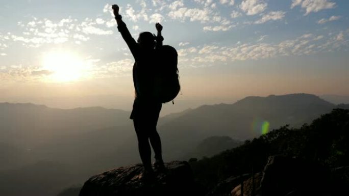 女人徒步到山顶，举起手来庆祝成功，慢动作