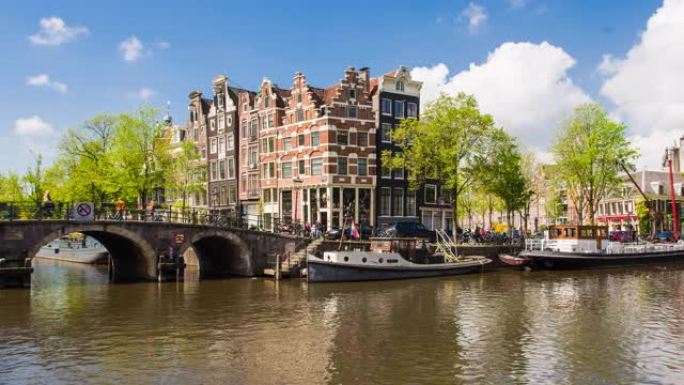 在美丽的晴天，荷兰阿姆斯特丹有船只和倾斜房屋的河渠