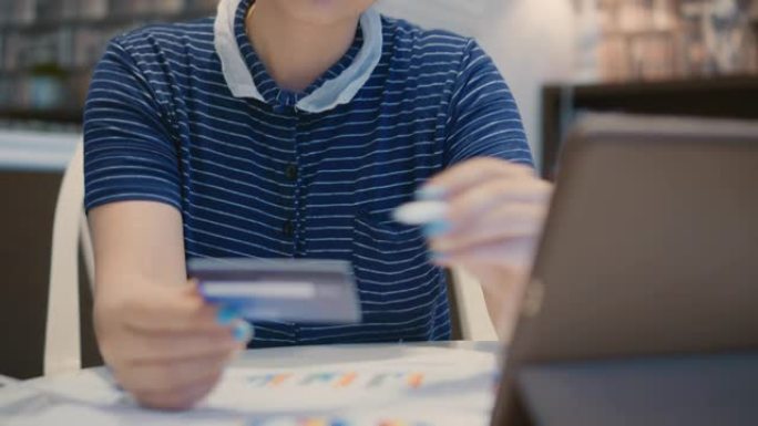 女商人用信用卡在数字平板电脑上购物，向下倾斜