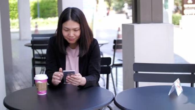 女商人使用手机在户外咖啡馆喝咖啡