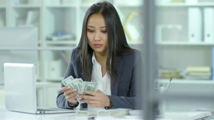 亚洲女会计师数美元和在笔记本电脑上工作