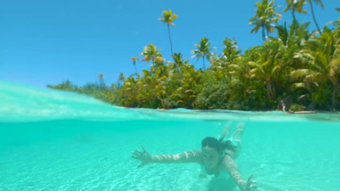 慢动作: 快乐的女人在绿松石海洋中的天堂岛潜水