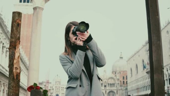 美丽的女性专业摄影师与相机在意大利威尼斯老城的木柱附近拍照。