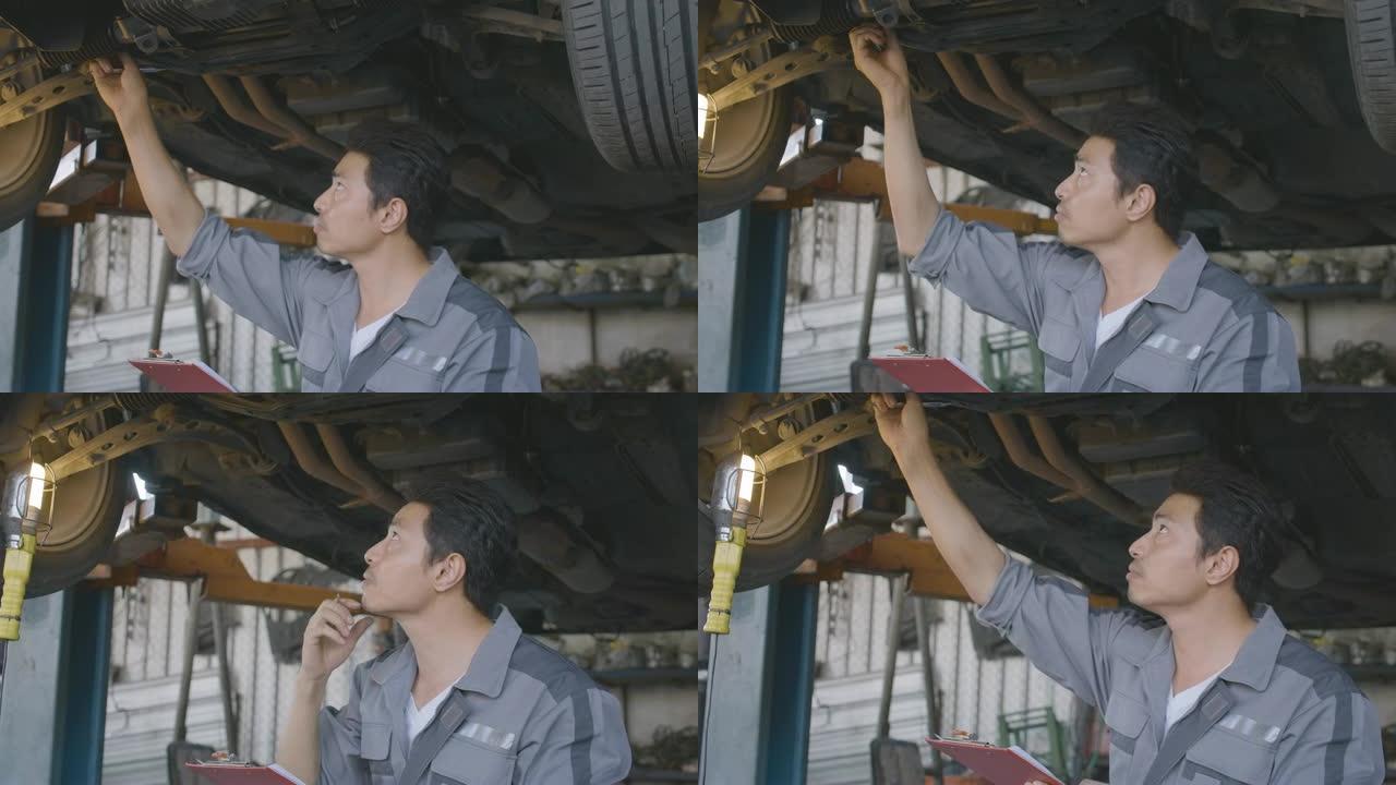 男汽车修理工在车库检查汽车底盘路，汽车服务理念。