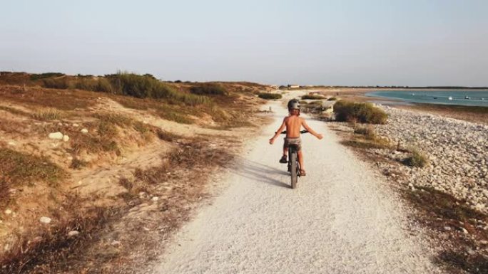 光着膀子的男孩喜欢在海滩骑自行车