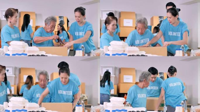 亚洲祖母年龄70岁的志愿者包装盒子免费送餐，而朋友包装衣服捐赠来自危机冠状病毒COVID-19.Vo