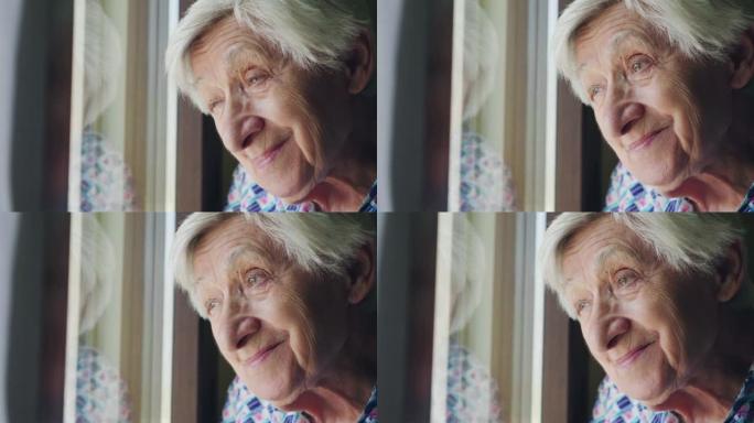 一位老太太看着窗外，微笑着。在窗户里。