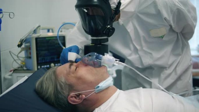 戴着氧气面罩的病人正在检查体温。医生在附近保护冠状病毒病人。