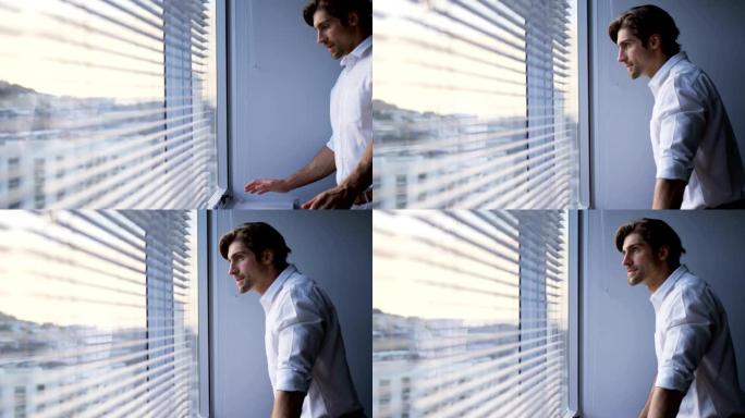 现代办公室4k中站在窗户附近的体贴年轻高加索男性高管的侧视图