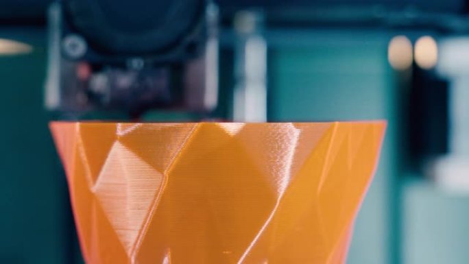 打印机制正在向橙色3d对象添加图层。三维3d打印机在3d打印实验室工作。