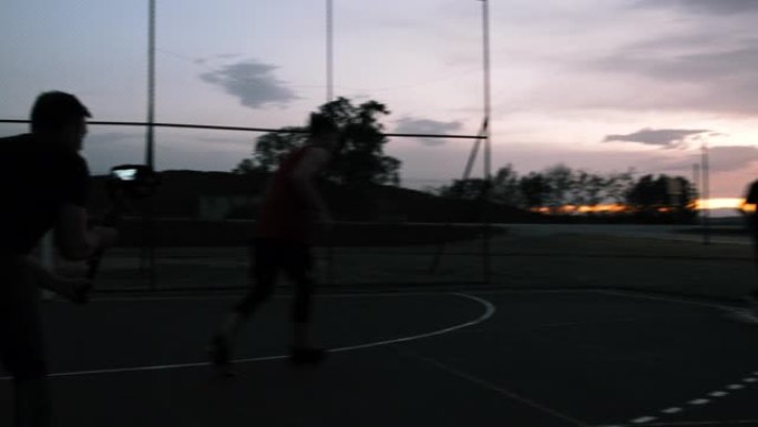 男子女士拍摄篮球运动员在黄昏时在室外篮球场上射击篮筐