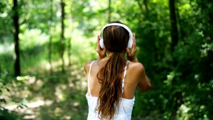 树林里的一个女人戴着耳机听音乐