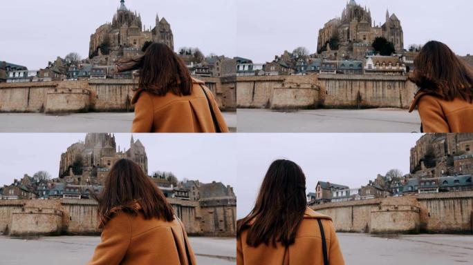 时尚博主女人走向法国令人惊叹的圣米歇尔山城堡地标慢动作的电影后视