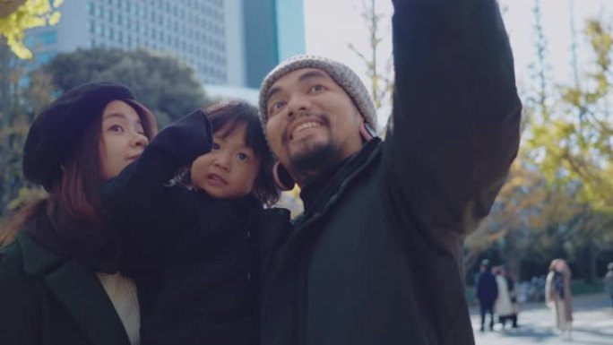 日本的家庭度假。父母和孩子在手机上自拍。