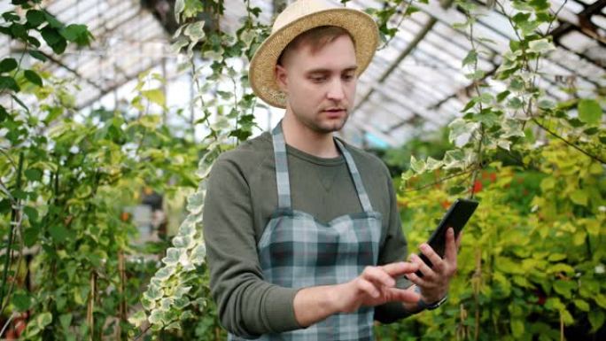 温室计数植物中使用平板电脑的年轻农民的慢动作