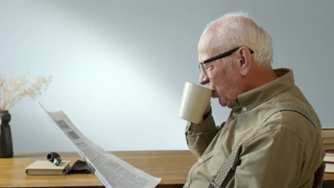 高年级男子喝咖啡看报纸