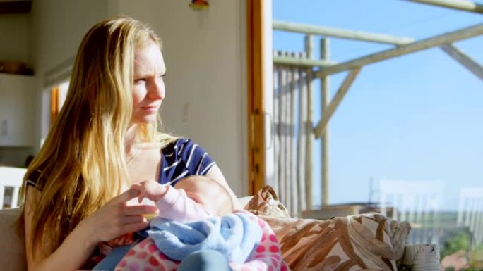 中年白人母亲在舒适的家庭4k从奶瓶里给婴儿喂奶的前视图
