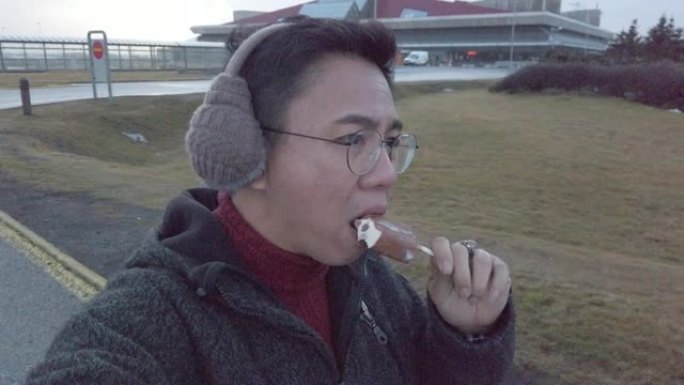 一名亚洲华裔男性在寒冷的天气里散步享受冰淇淋