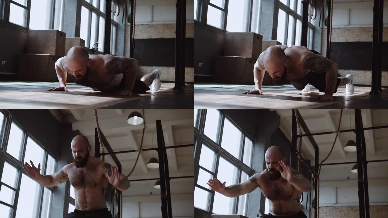 年轻强壮的肌肉赤膊白人男性运动员在大型健身房进行功能性锻炼时做burpee锻炼。