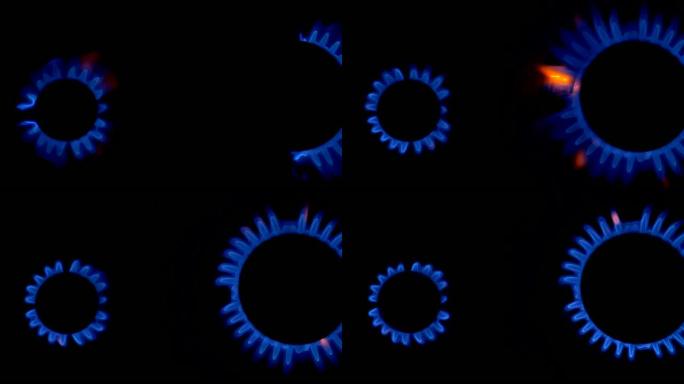 燃气灶的两块面板慢慢燃烧着蓝色的火。黑色背景上的蓝色和黄色热火焰燃烧器。慢动作