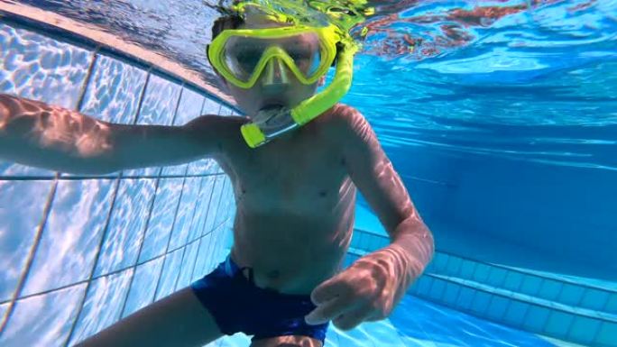 一个男孩戴着潜水面具漂浮在游泳池里