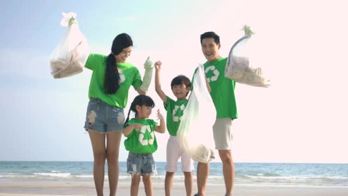 一群穿着绿色t恤的志愿者用装满垃圾的塑料袋清理海滩。慢动作。安全生态概念。4k分辨率。
