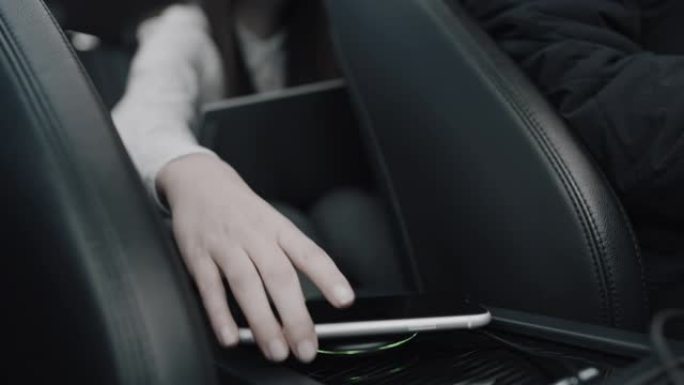 女士女士在汽车上的无线充电器上给智能手机充电