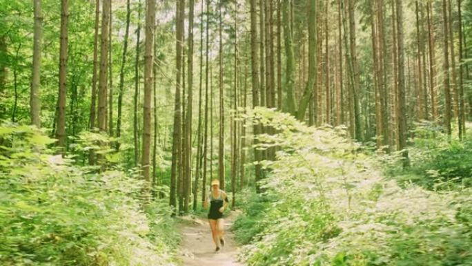 在阳光明媚的日子里，SLO MO女人在森林里奔跑