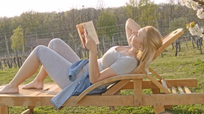CU给无忧无虑的年轻女子放松和阅读阳光樱花树下的书