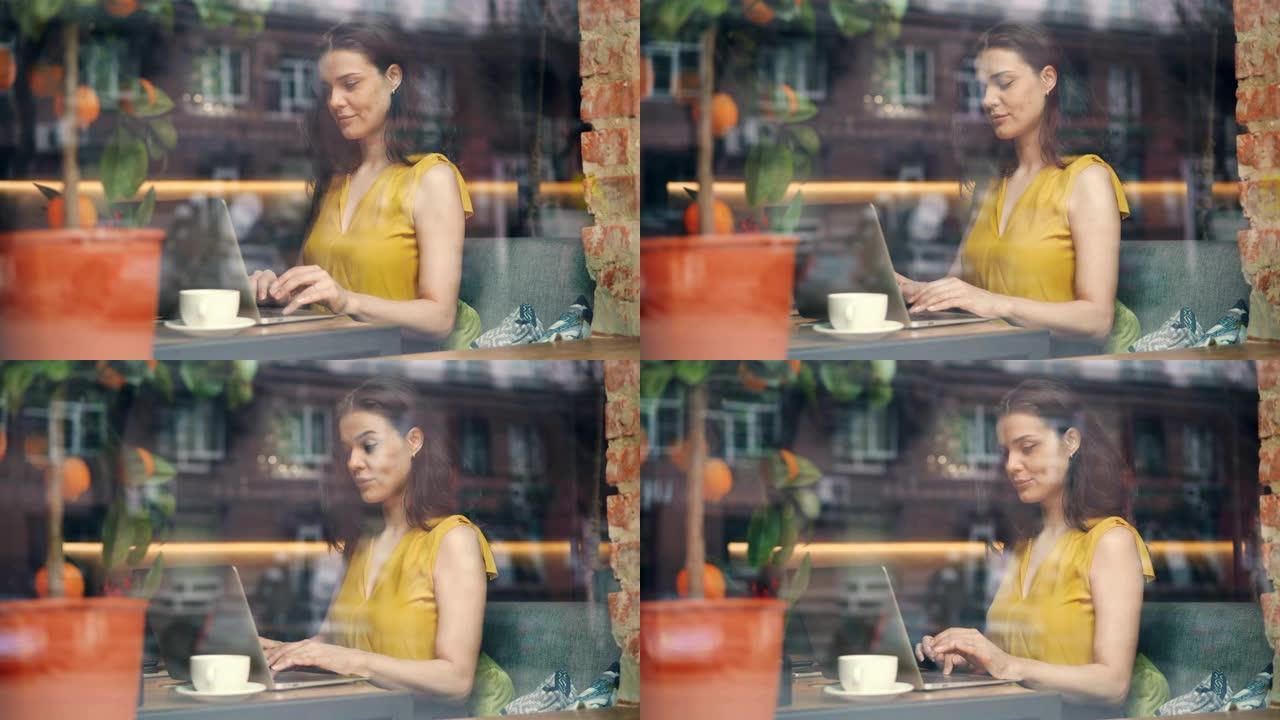 微笑的女孩在咖啡馆里用笔记本电脑打字，专注于活动