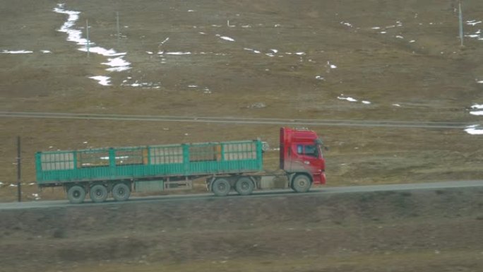 带空拖车的旧红色卡车，用于运输牲畜，沿着风景秀丽的道路行驶