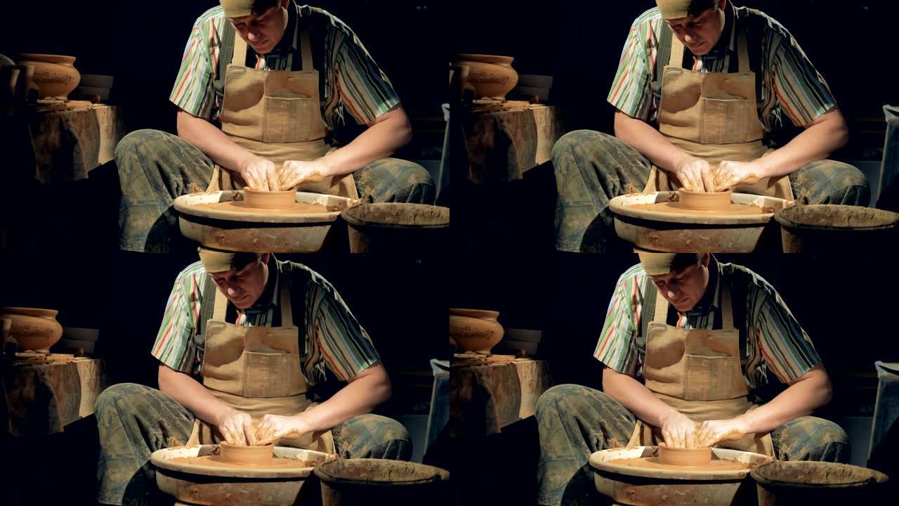 陶艺人创造了一个碗。一个人在陶器上工作，在轮子上做一个粘土碗。
