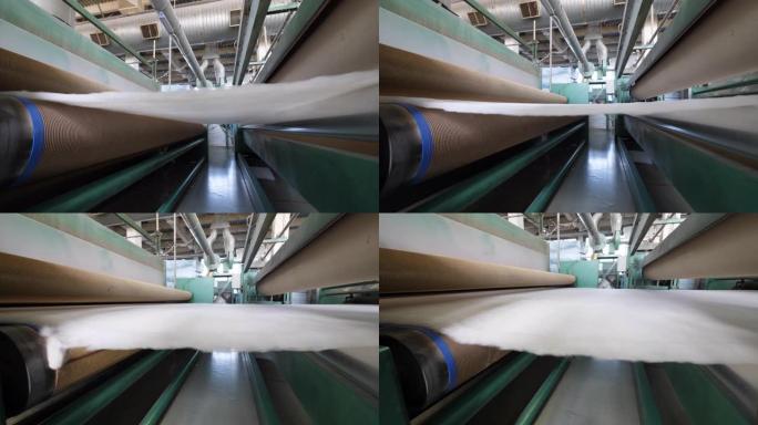 在工厂工作时，金属辊移动白色聚酯织物。