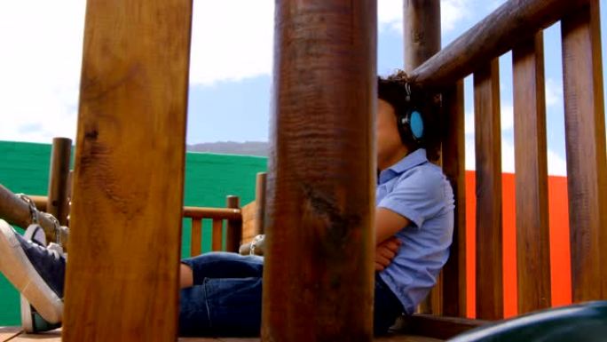 混血女学生在学校操场4k戴着耳机听音乐的侧视图