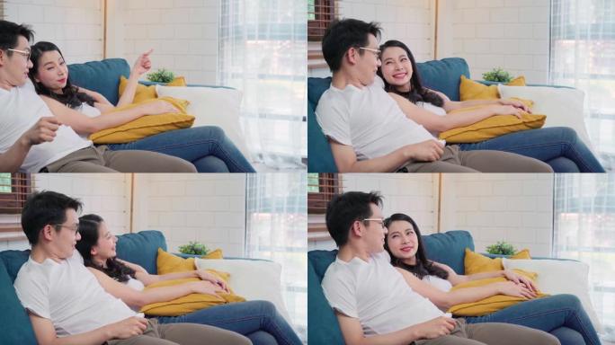亚洲情侣在家里的客厅拥抱在一起，甜蜜的情侣在家放松时躺在沙发上享受爱情时刻。生活方式夫妇在家放松的概