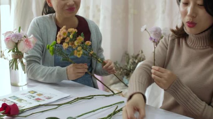 年轻的花店正在训练她的朋友如何制作花束