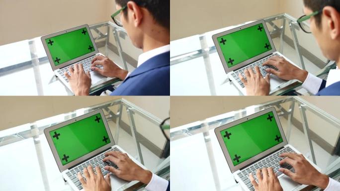 商人在带有绿色屏幕的笔记本电脑上打字