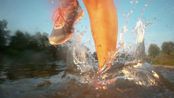 特写: 女性慢跑者在平静的溪流中奔跑时溅起纯净水。