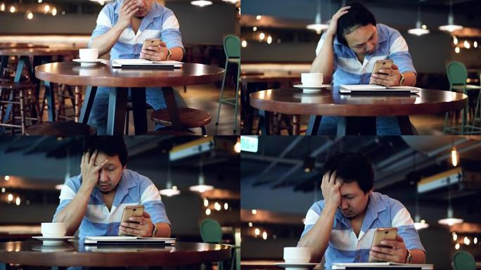 4k镜头亚洲商人穿着休闲服工作和患有抑郁症的场景与智能手机在共同工作空间，商业健康和压力概念