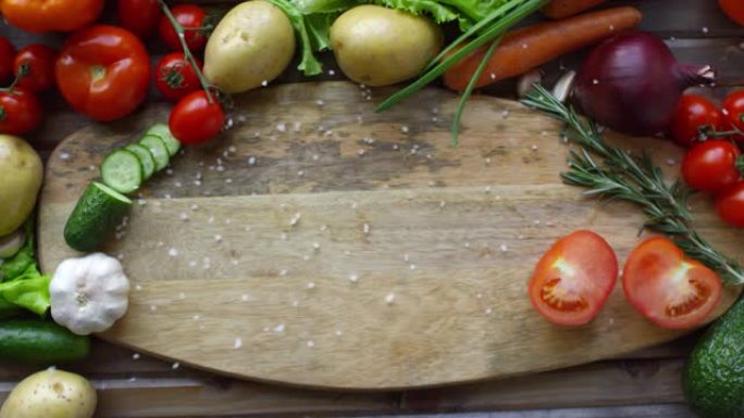 盐落在新鲜蔬菜包围的木板上