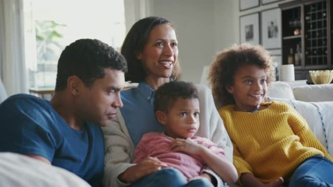 年轻的家庭一起坐在客厅的沙发上看电视和聊天，特写镜头