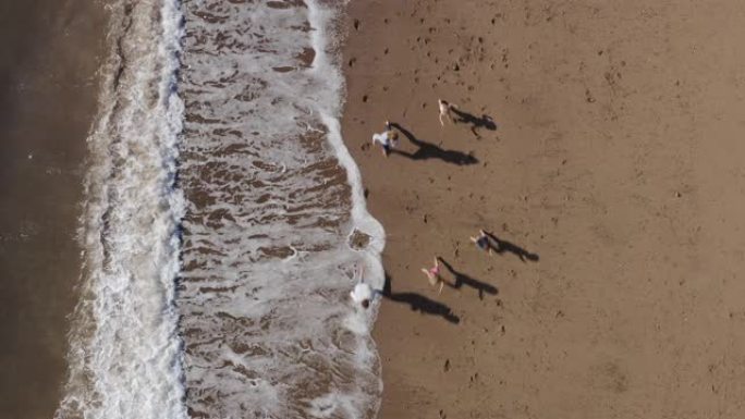 通过破浪在海滩上度假的家庭拍摄的无人机