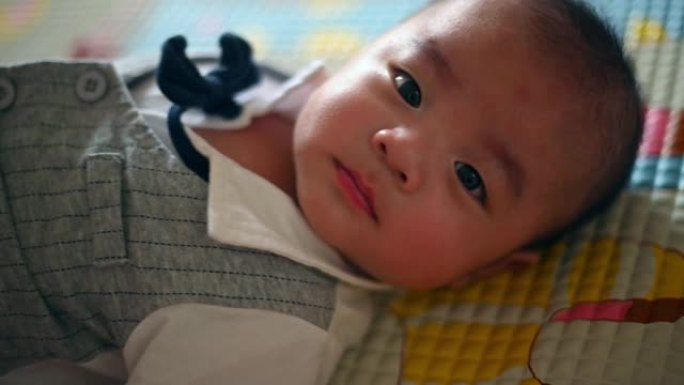 一个可爱的亚洲中国5个月大男婴躺在床上看着相机