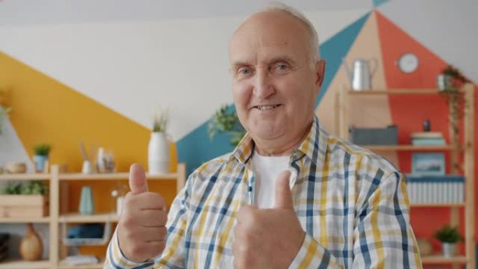 穿着休闲服装的退休男子的慢动作肖像在家里显示竖起大拇指的手势