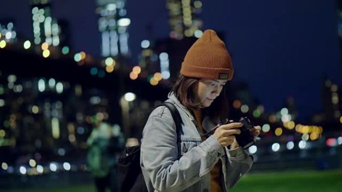 年轻的亚洲女性在河边用数码相机拍照。