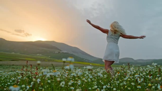 WS超级慢动作快乐的年轻女子在田园诗般的草地上旋转，野花，翁布里亚，意大利