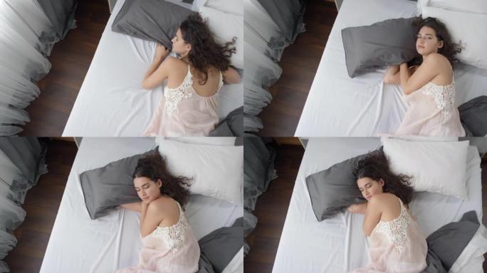 年轻性感女人躺在床上看着相机的俯视图