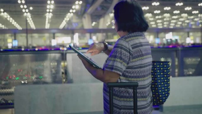 亚洲高级女性在机场停车时使用平板电脑