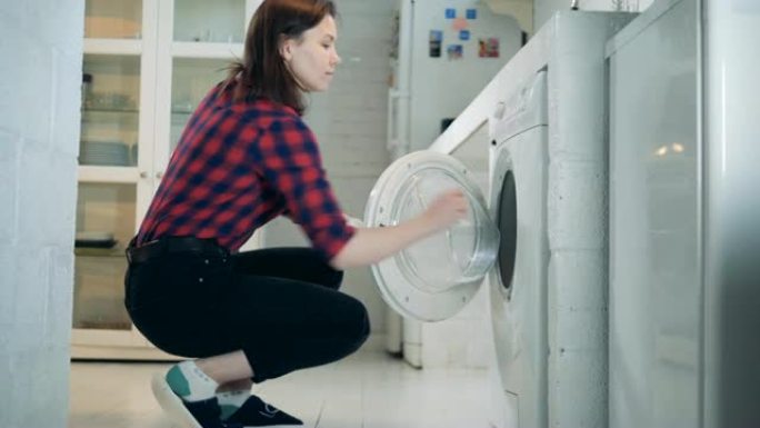 有着仿生手臂的年轻女子正在从洗衣机里拿衣服