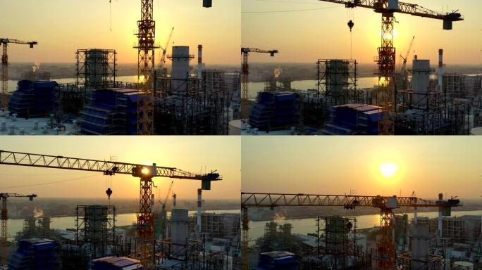 日落时分，联合循环发电厂塔式起重机和冷却塔的施工现场鸟瞰图